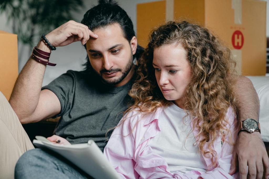 Couple sitting together reviewing a preparedness checklist, making calm decisions in a home environment