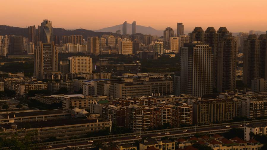 Urban skyline at sunset with layered high-rise buildings in neutral tones, illustrating how gray man clothing helps individuals blend in during city-based emergencies and maintain low visibility in high-density environments. Wide view of a dense urban skyline at sunset, with layered high-rise buildings in muted tones under an orange sky: an example of an environment where gray man attire helps one move unnoticed through varied social and architectural landscapes.